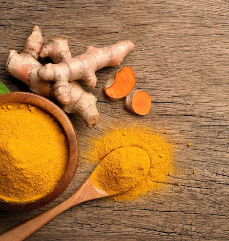 flat-lay-top-view-turmeric-curcumin-powder-wooden-bowl-spoon-with-fresh-rhizome-wood-background_252965-741